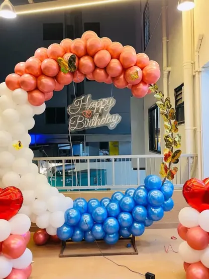 A unique tri-color balloon ring for a terrace party. The arch is divided into sections of pink, white, and blue, with heart-shaped balloon pillars on each side.