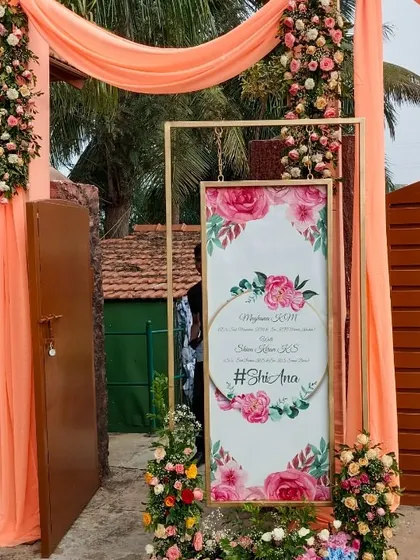 A personalized welcome sign for a wedding, framed by peach-colored drapes and floral arrangements.