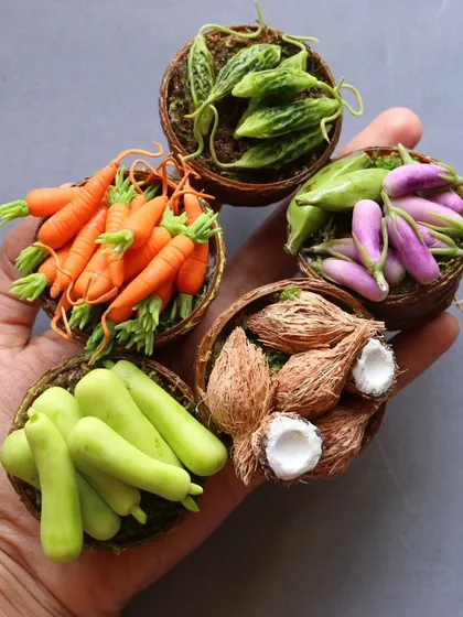 A hand holding five baskets of miniature vegetables, showing the incredible realism and detail.