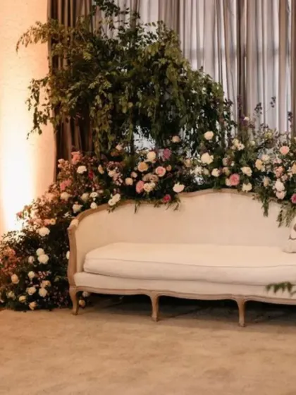 A romantic seating area for a Nikkah or Walima, with a sofa framed by cascading greenery and flowers.