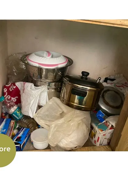 This lower cabinet was being used to store a mix of pots, plastic bags, and other miscellaneous items.