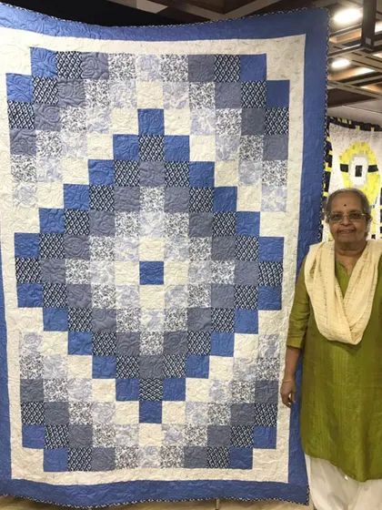 A happy client with her finished "Trip Around the World" quilt in shades of blue.