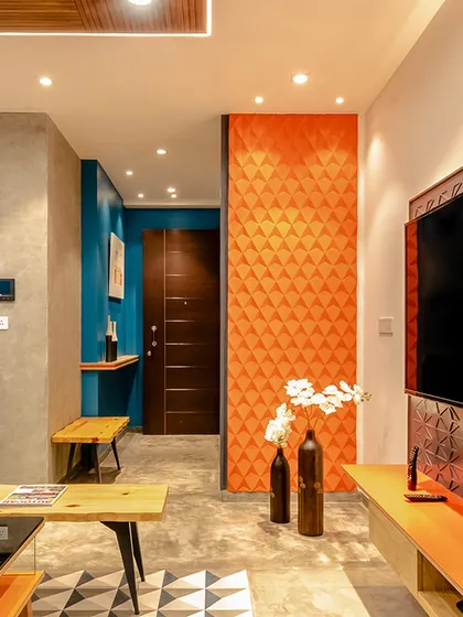 An orange 3D-paneled wall serves as a vibrant focal point in this living room, showcasing how a single, bold material choice can define a space.