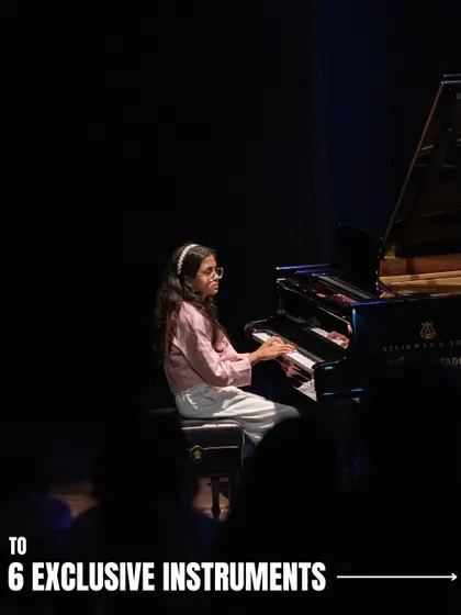 A young pianist performs on a grand piano at 'Holiday in Harmony'. Our musicals give students the opportunity to play on professional quality instruments in a real theatre.