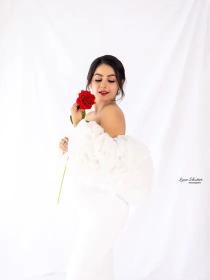 A close-up to capture that beautiful pregnancy glow. The soft fabric of the white gown and the delicate touch of the rose add a touch of timeless romance to this maternity portrait.