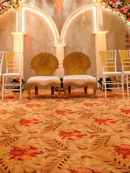 The arc-shaped structures and seashell-inspired chairs serve as a perfect royal-themed backdrop for the wedding couple.