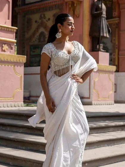 A closer look at our stunning ivory pre-draped saree with a fully beaded tassel blouse. It's a modern, high-fashion take on the classic white saree.