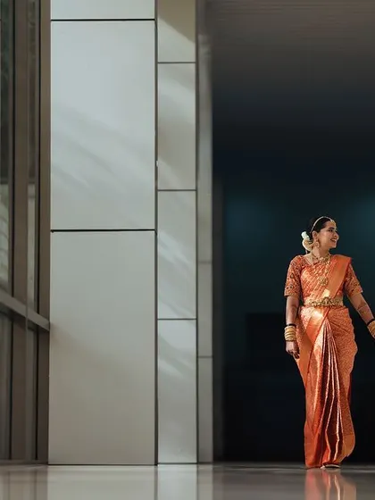 A candid moment of the couple walking hand-in-hand through a modern corridor. The play of light and shadow adds a cinematic quality to this simple, everyday gesture of love.
