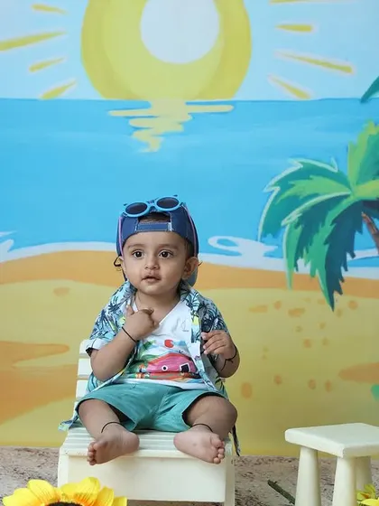 The toddler is back in his cap and sunglasses, ready for more fun beach poses.