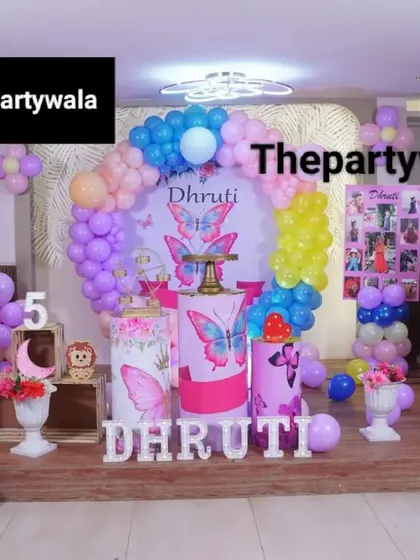 A wide shot of a butterfly and fairy-themed party, showing the full stage and colorful decor.