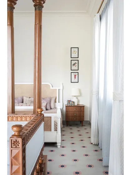 The daughter's bedroom combines elegance and simplicity, with a beautiful white four-poster bed and custom cement tiles that add a soft touch of color.