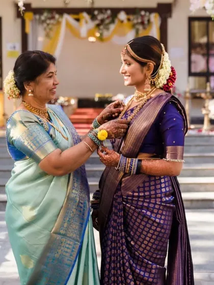 A mother and daughter sharing a special moment, both dressed in custom Kalasthree outfits for a wedding.