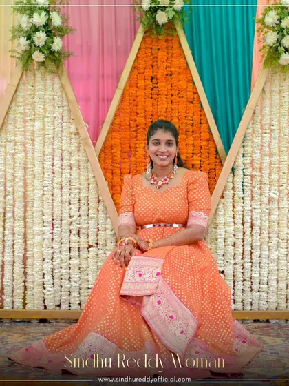 A client looking radiant in a custom orange Banarasi gown, perfect for a festive celebration.