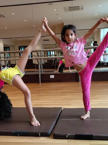 Gymnastics is more fun with friends! These two young athletes show off their amazing flexibility and balance together.