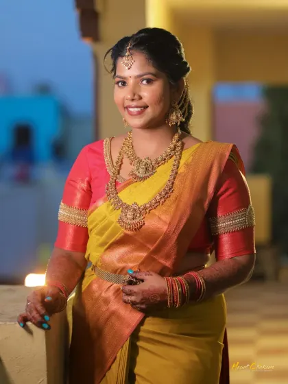 A smiling portrait of the bride-to-be at her engagement, looking radiant in her yellow and pink saree.