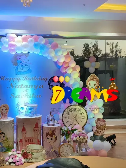 A wide view of a princess-themed party hall decoration. This shows the main stage with a castle, a separate photo booth frame, and coordinated balloon arrangements throughout the space.