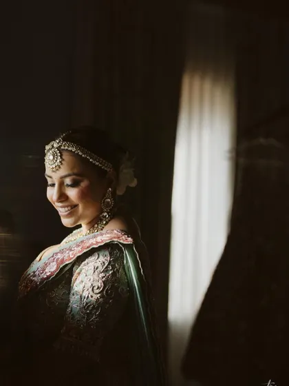 A beautiful, softly lit portrait of the bride, her smile illuminated as she looks down. The lighting creates an intimate and artistic feel.