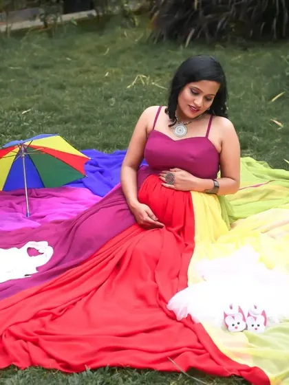 A close-up of a mom-to-be cradling her bump in the rainbow gown. This image highlights the comfortable fit and rich colors of the dress, perfect for maternity portraits.