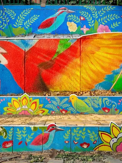 This vibrant mural in Noida Sector 27 features a large macaw and other birds amidst colorful flora. The goal was to bring the beauty of the jungle to the city walls.
