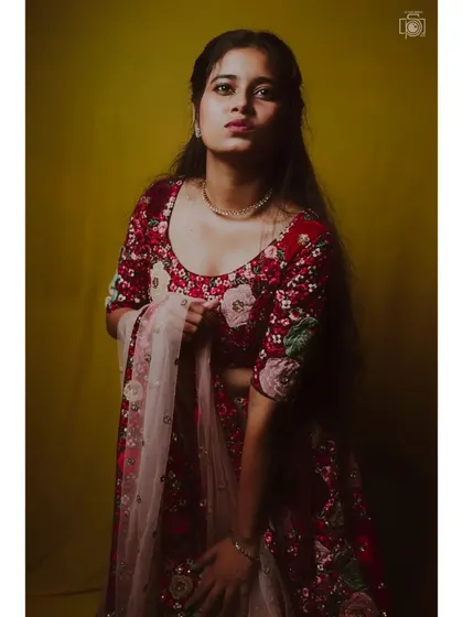 A studio portrait where we used a warm, yellow-toned background to complement the red floral lehenga. The lighting is carefully set up to highlight the model's features and the texture of the outfit.