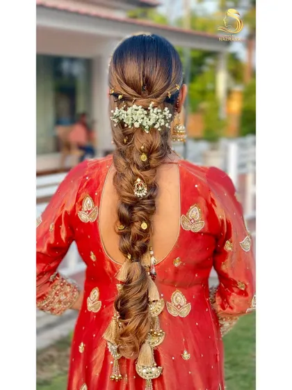 A closer look at the decorated messy braid, showing the combination of floral and traditional accessories.
