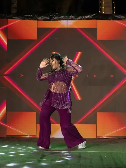 A solo dance performance captured with a vibrant, graphic LED screen in the background, highlighting the energy of the Sangeet.