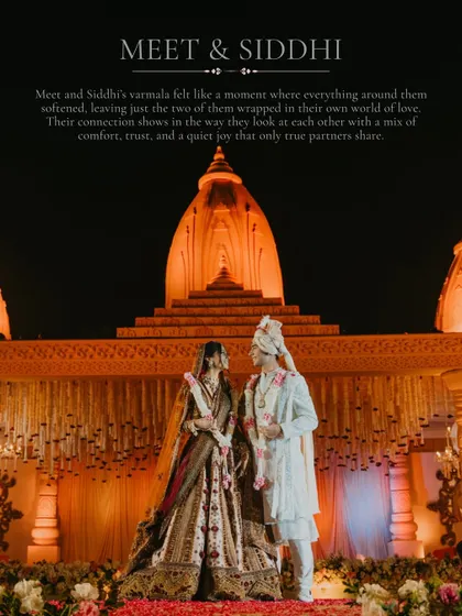 A grand, wide-angle shot of the varmala ceremony against a beautifully lit temple-like backdrop. This image showcases our skill in capturing the scale and atmosphere of a luxurious wedding.