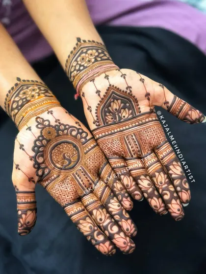 A lovely design featuring classic henna elements. The palm showcases a peacock mandala, while the fingers are decorated with lotus patterns, all tied together with intricate line work.