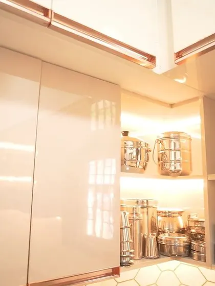A close-up of the illuminated open shelving in the U-shaped kitchen, perfect for displaying decorative kitchenware. The rose-gold cabinet profiles add a subtle touch of luxury.
