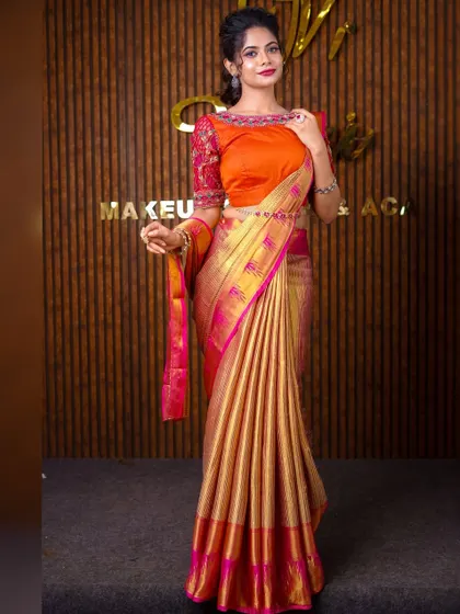 A full-length shot of a model in a gold and pink silk saree. The pallu is styled to be worn open over the arm, creating a very graceful and classic pose.
