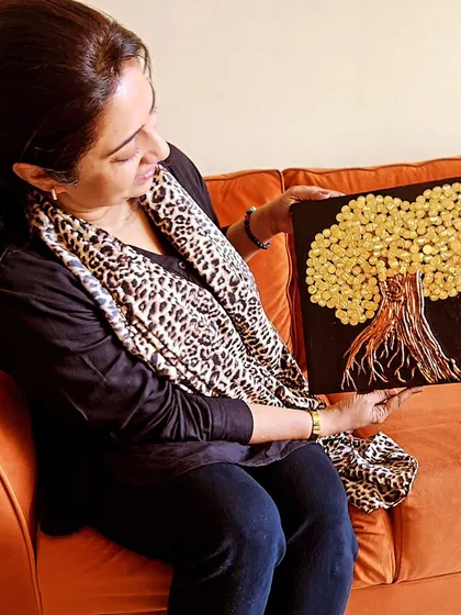 A happy client with her completed Abundance Tree painting. This piece, with its golden leaves against a dark background, is designed to be a powerful focal point for attracting wealth.