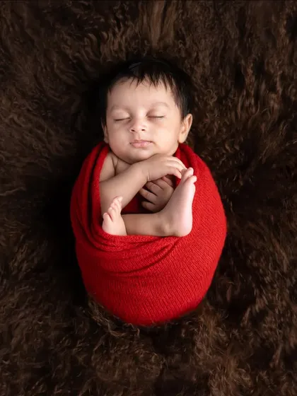 Wrapped in a bold red swaddle, this baby is the perfect centerpiece. The soft brown fur creates a beautiful contrast, making the little one stand out.