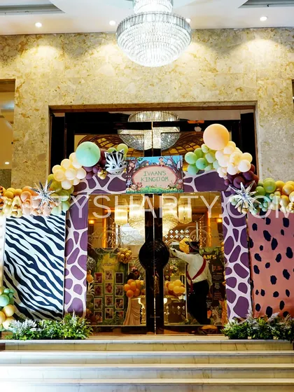 We create an immersive jungle experience with detailed entrance decor. This archway is covered in giraffe and zebra print panels, accented with balloon garlands and animal cutouts, setting the stage for a wild adventure.