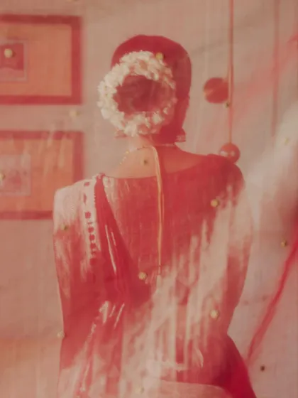 An artistic portrait of the bride, seen through her red veil. The soft focus and dreamy quality of the image capture the feeling of a memory, a gentle glimpse of the bride before she steps into her new life.
