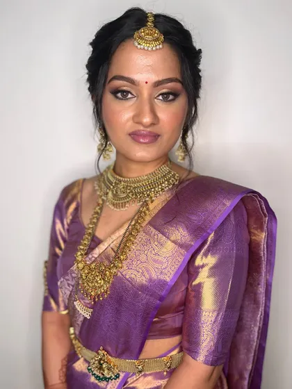 A portrait of the bride looking directly at the camera, showing off her flawless makeup and stunning jewelry.
