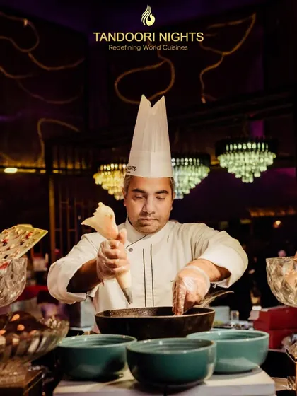 The secret behind our renowned flavors: our chef’s touch of perfection in every bite. Here, a chef is seen preparing a dessert with intense focus.