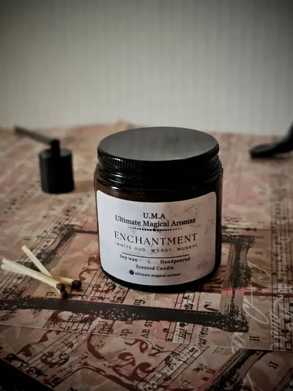 A simple, elegant shot of the 'Enchantment' candle with its accessories. This woody and musky fragrance is a sophisticated choice for any home.