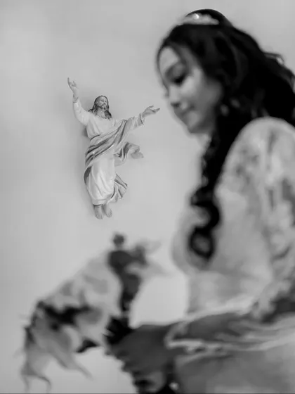 An artistic black and white shot of the bride, with a statue of Jesus in the background, symbolizing a moment of prayer and reflection.