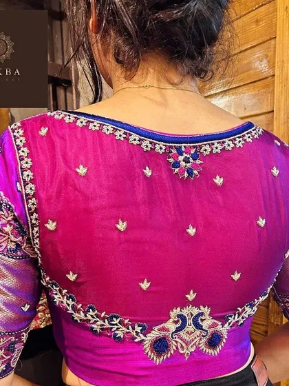 A modern and elegant design featuring a sheer net back on a magenta blouse. The delicate floral embroidery along the border and scattered motifs create a subtle yet captivating look.