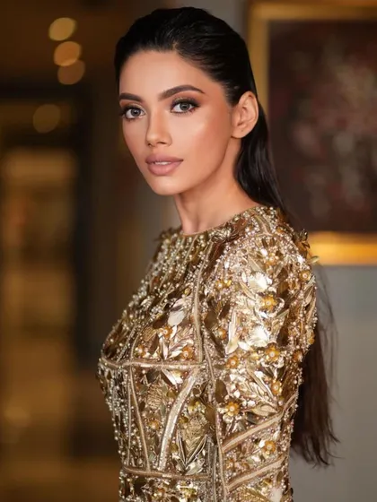 A close-up of a high-glam, golden goddess look. This style features a wet-look hair finish and luminous, bronzed skin, perfect for a cocktail or reception event.