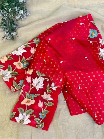 A red brocade and sheer tulle blouse, featuring bright lotus motifs.