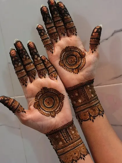 A beautiful mandala design on the palms, complemented by intricate wristbands. The symmetry of the mandalas is very pleasing to the eye.