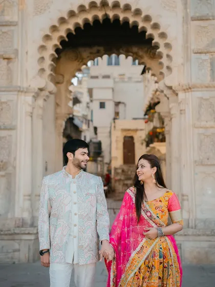 A candid shot of the couple walking hand-in-hand through an arched gateway in Udaipur, creating a sense of journey and togetherness.