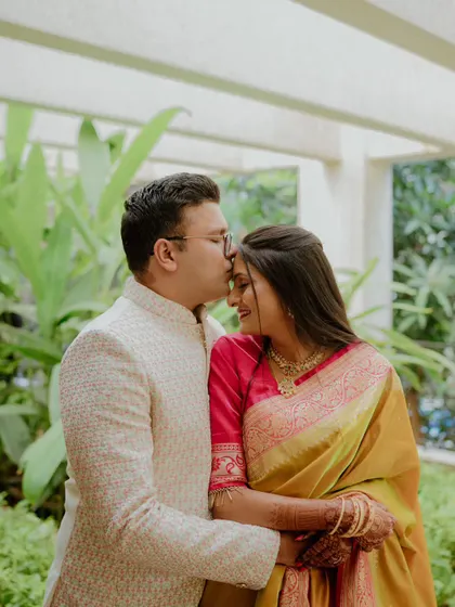 A tender moment as the groom-to-be kisses his fiancée's forehead. This gentle gesture, combined with their elegant traditional outfits, creates a timeless and romantic portrait.
