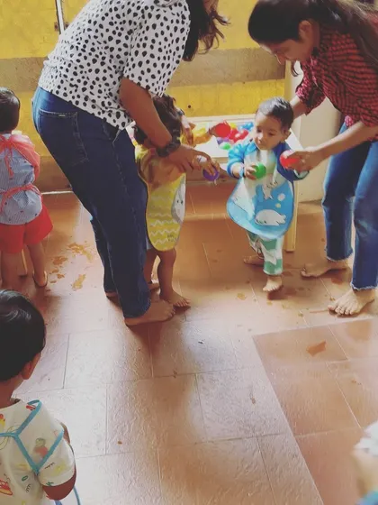 Instructors assist toddlers at the water play station, ensuring they are safe and comfortable. This support helps build confidence in young children as they try new activities.