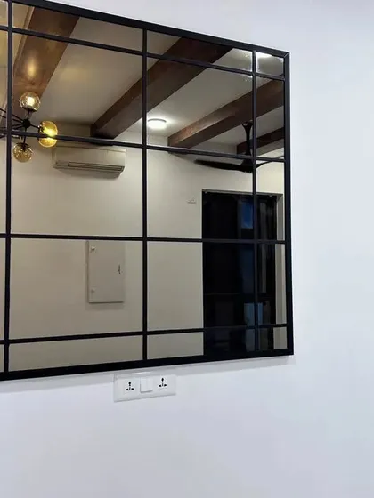 A large, black-framed panelled mirror. This kind of statement piece can be used in a living room, hallway, or bedroom to add depth and a touch of industrial chic.