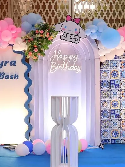 A cute Kuromi-themed party with a central white arch and a "Happy Birthday" neon sign, flanked by character cutouts.