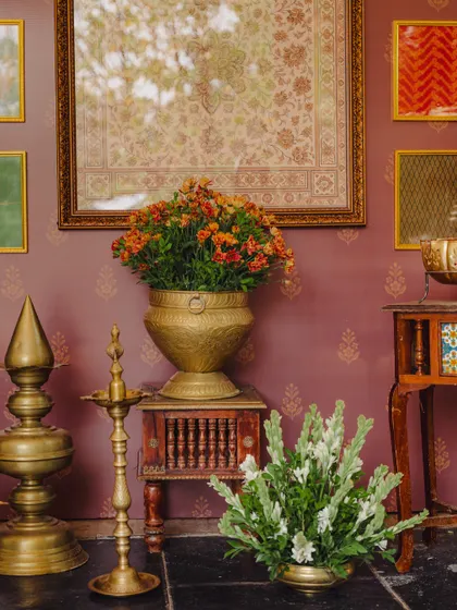 A beautifully styled corner in a heritage venue, featuring brass lamps, floral arrangements, and framed art against a rich purple wall.