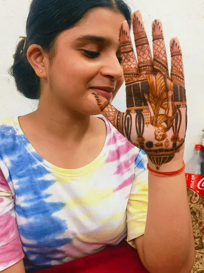 A happy client showing off her Karwa Chauth mehandi. The design features a woman looking at the moon, a classic theme for the festival.