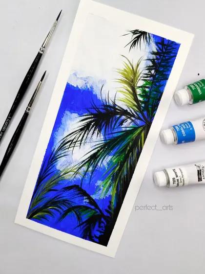 The finished mini palm tree painting next to the acrylic paints I used. It's a simple but vibrant piece that captures a tropical feel.